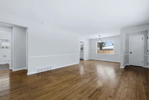 an empty room with wooden floor ceiling fan and windows