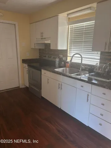a kitchen with granite countertop white cabinets and a sink