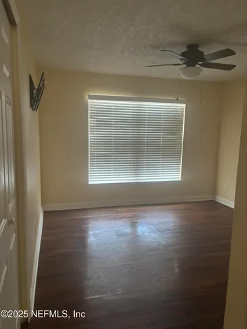 a view of empty room with wooden floor and fan
