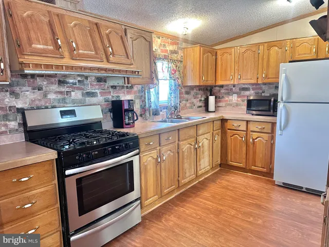 a kitchen with stainless steel appliances granite countertop a stove a sink dishwasher and a refrigerator