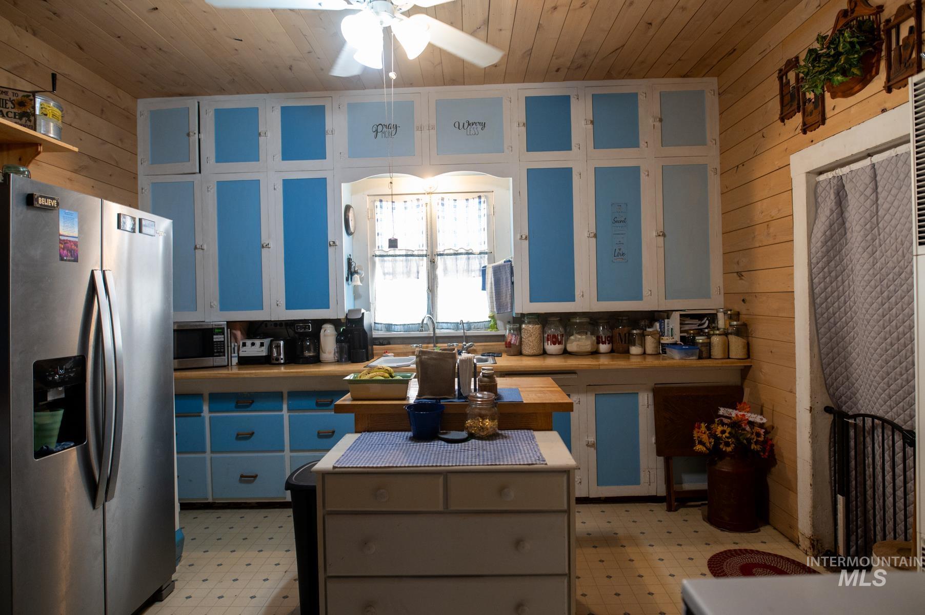 736 East Main Street Weiser, ID 83672 - Photo 19 of 33 Kitchen featuring light blue and white cabinetry, wood-finish countertops, and wood-paneled walls