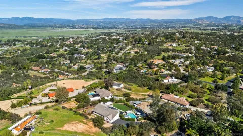 an aerial view of residential houses with outdoor space and trees
