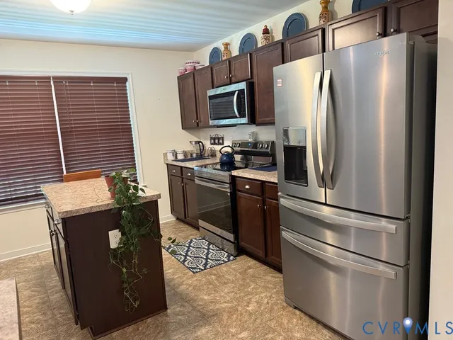 a kitchen with stainless steel appliances granite countertop a refrigerator a stove a sink and a microwave