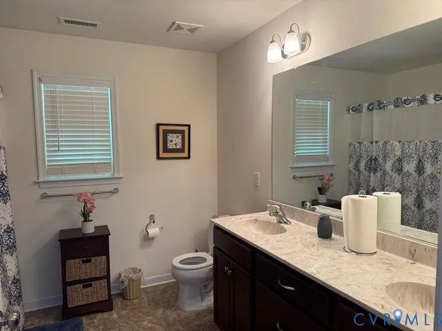 a bathroom with a granite countertop sink and a toilet