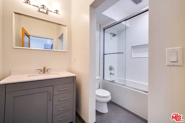 a bathroom with a granite countertop sink toilet a mirror and shower