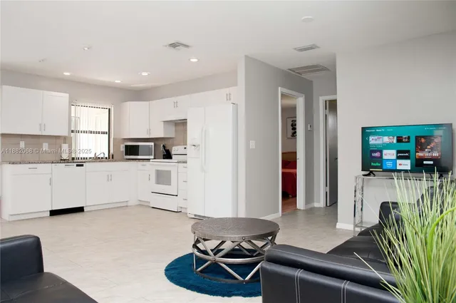 a living room with furniture a flat screen tv and kitchen view