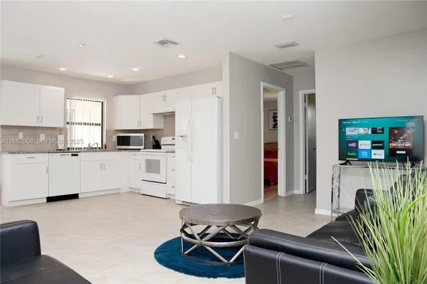 a living room with furniture a flat screen tv and kitchen view