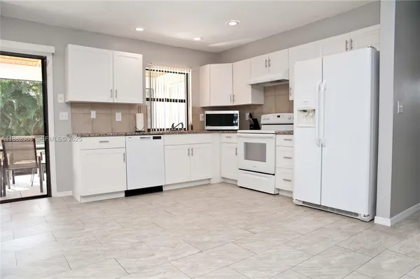 a kitchen with white cabinets and white appliances