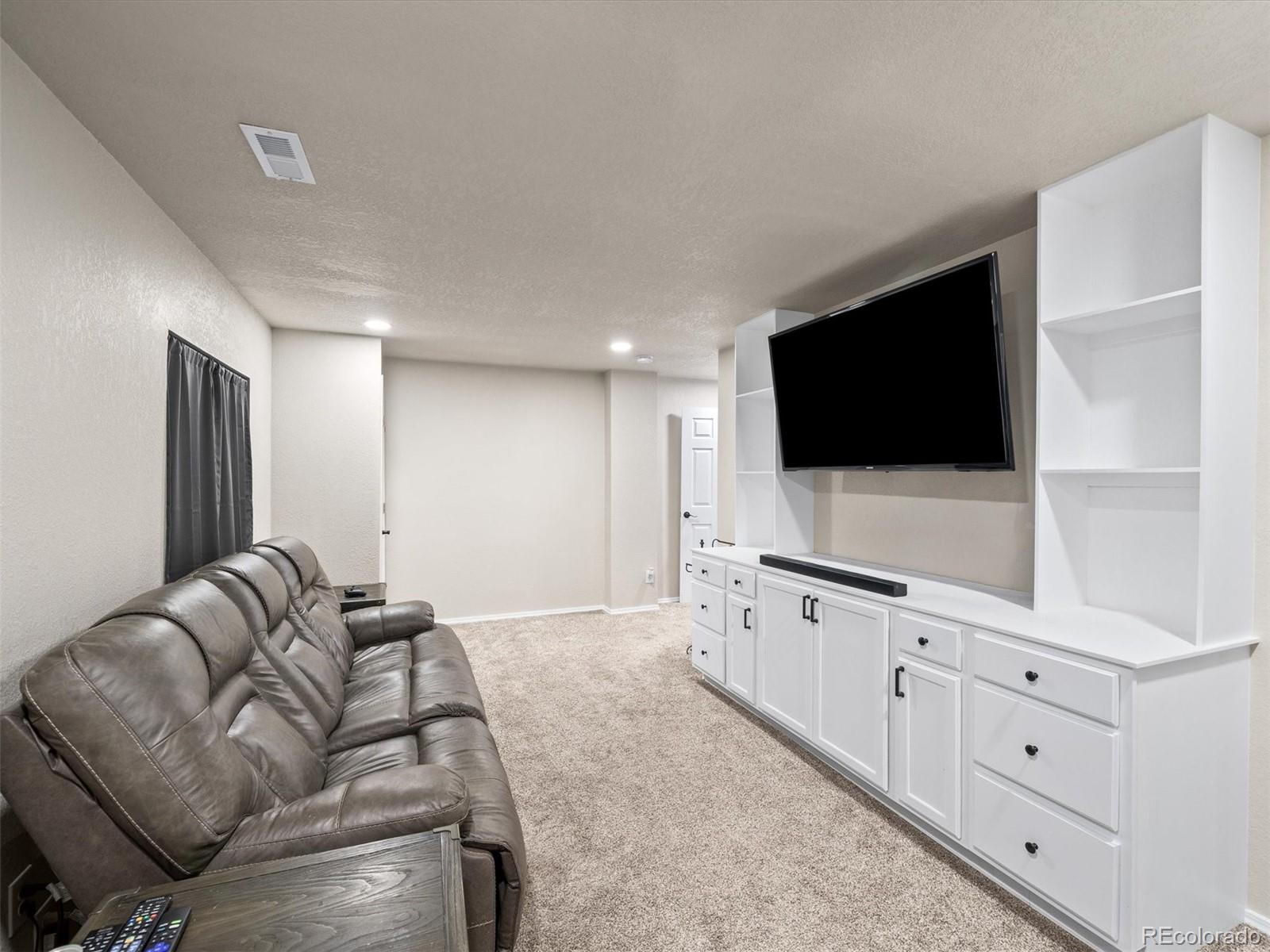 1940 Basil Street Strasburg, CO 80136 - Photo 32 of 38 a living room with furniture and a flat screen tv
