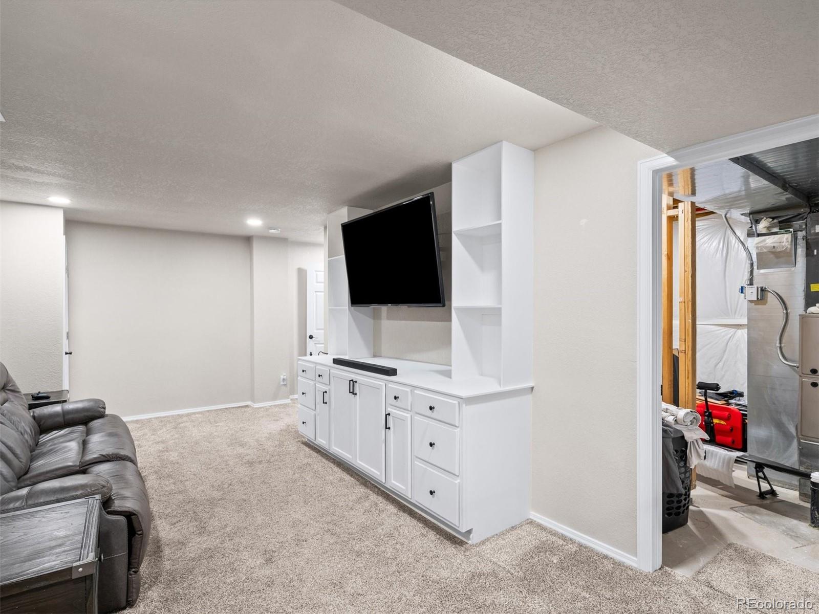 1940 Basil Street Strasburg, CO 80136 - Photo 33 of 38 a living room with furniture and a flat screen tv
