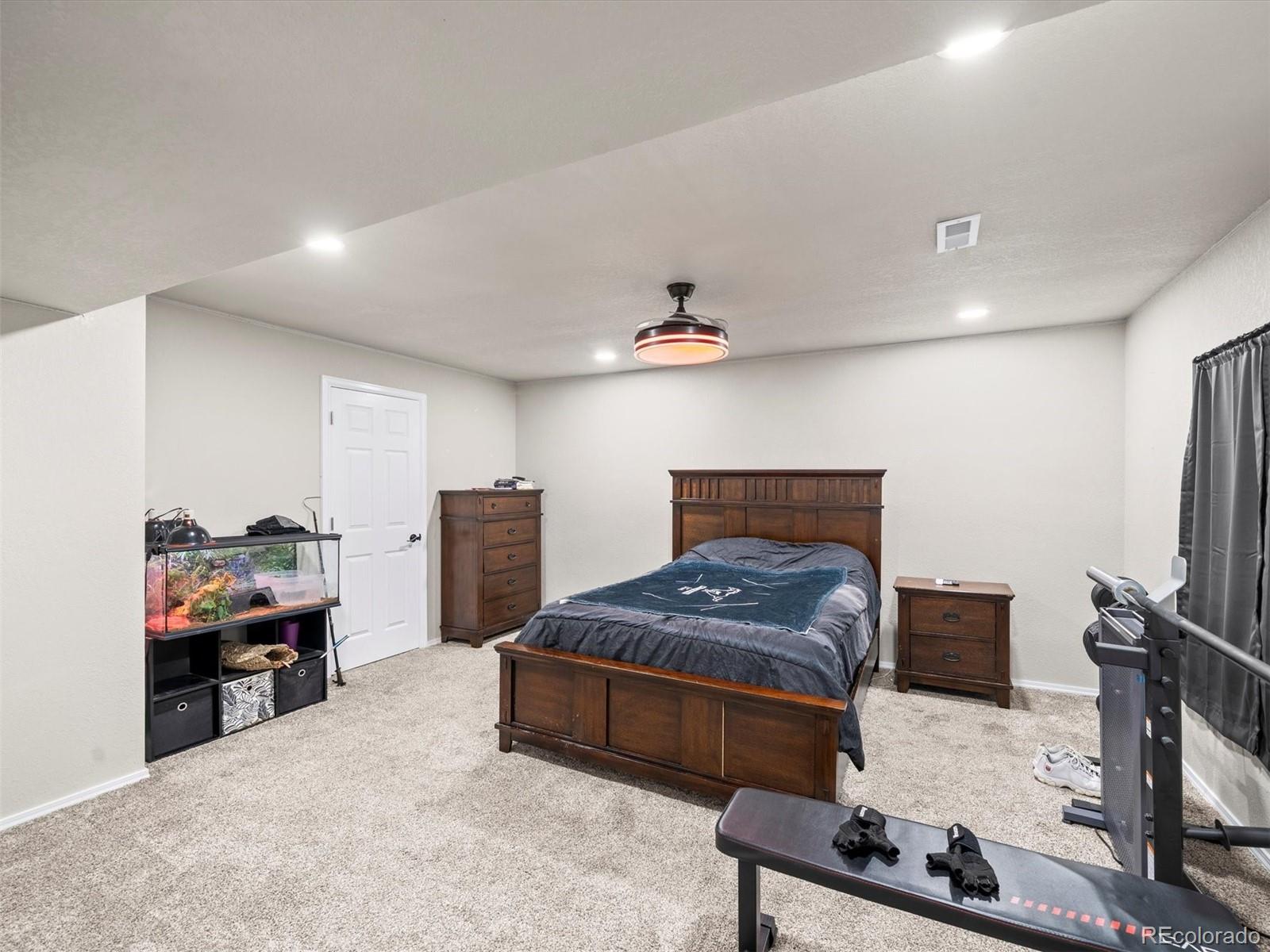 1940 Basil Street Strasburg, CO 80136 - Photo 34 of 38 a bedroom with furniture and a flat screen tv