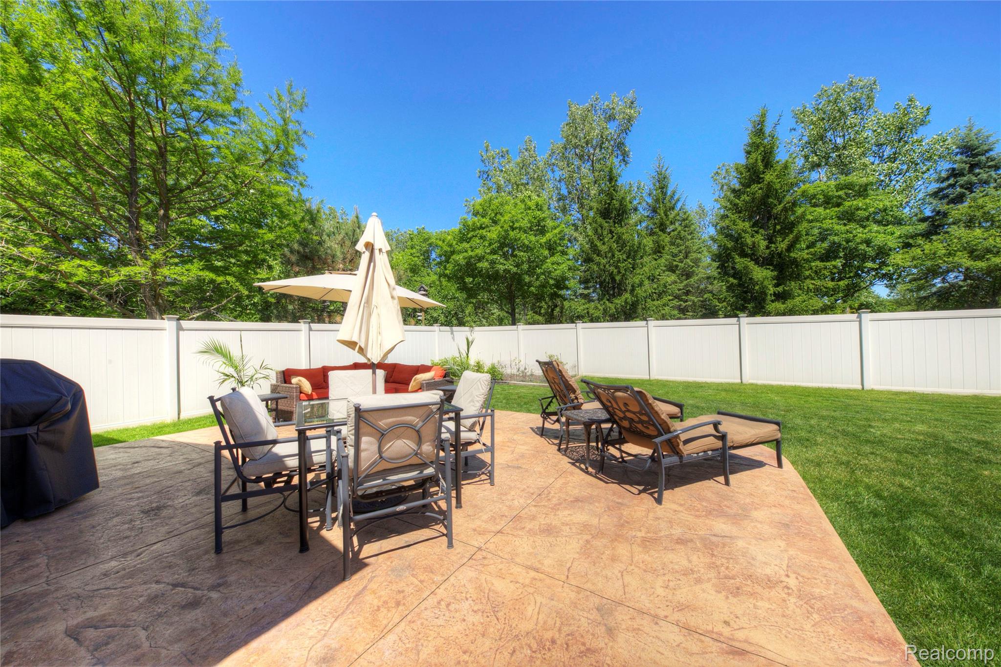 44570 Ridgefield Road Canton, MI 48188 - Photo 30 of 31 Expansive stamped concrete patio featuring multiple seating areas, a privacy fence, and a manicured lawn
