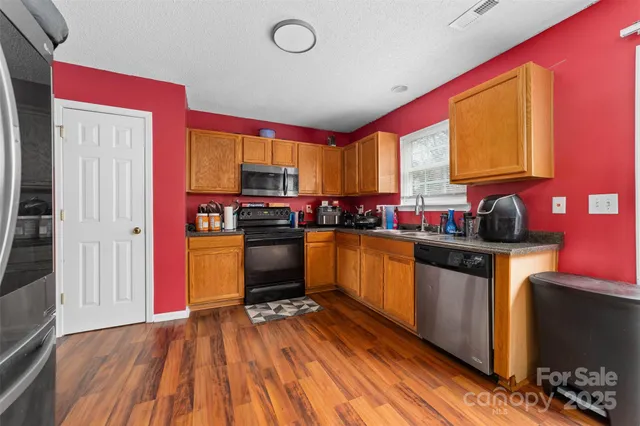 a kitchen with stainless steel appliances a stove top oven a sink and cabinets with wooden floor