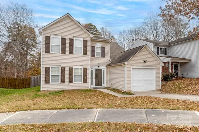 a view of a white house with large trees next to a yard
