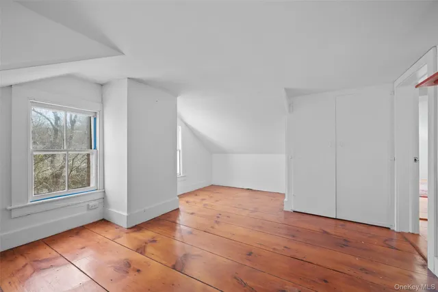 a view of an empty room with window and wooden floor