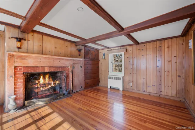 a view of an empty room with wooden floor fireplace and a window