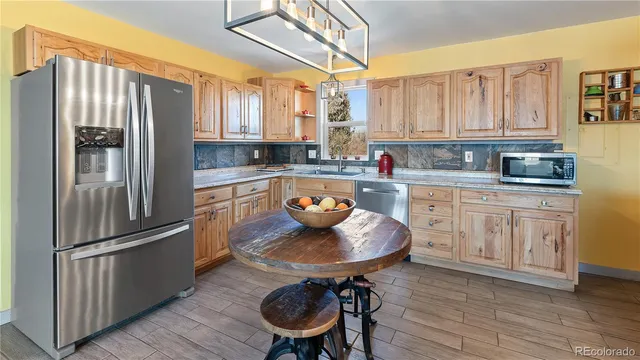 a kitchen with stainless steel appliances a refrigerator a stove a sink and white cabinets with wooden floor