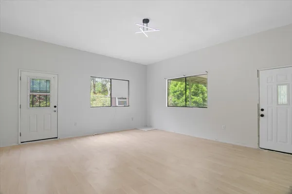 a view of an empty room with wooden floor and a floor to ceiling window