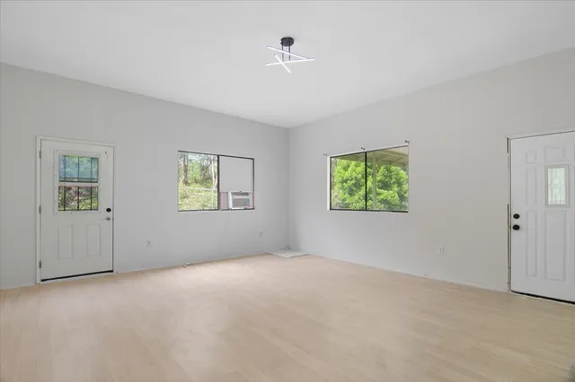 a view of an empty room with wooden floor and a floor to ceiling window