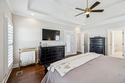 a bedroom with a bed a flat screen tv and a chandelier