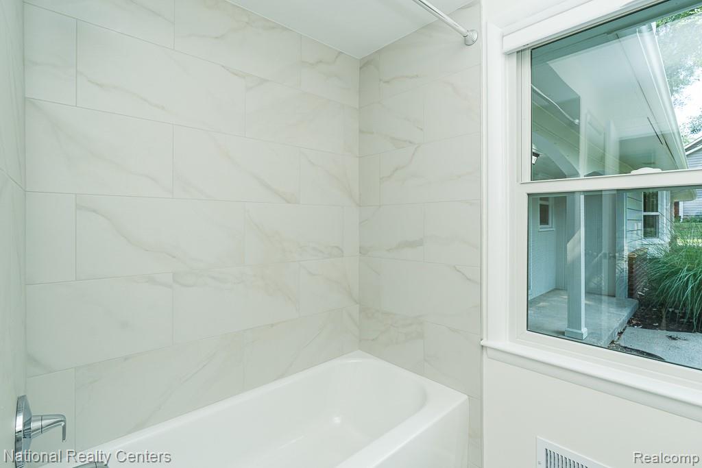 144 West Maryknoll Road Rochester, MI 48309 - Photo 29 of 38 Bathtub with white subway tile surround, chrome fixtures, and a single-hung window with white trim