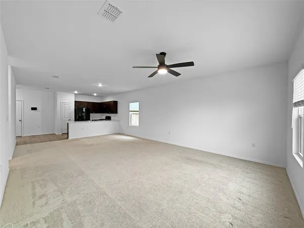 an empty room with chandelier fan and wooden floor