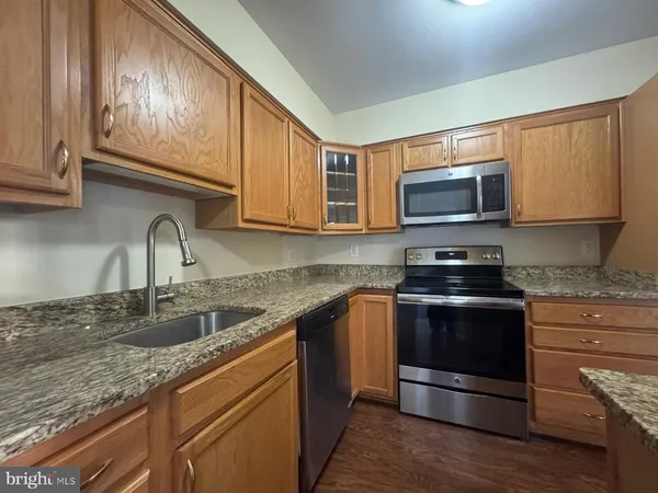 a kitchen with stainless steel appliances granite countertop a stove microwave and sink