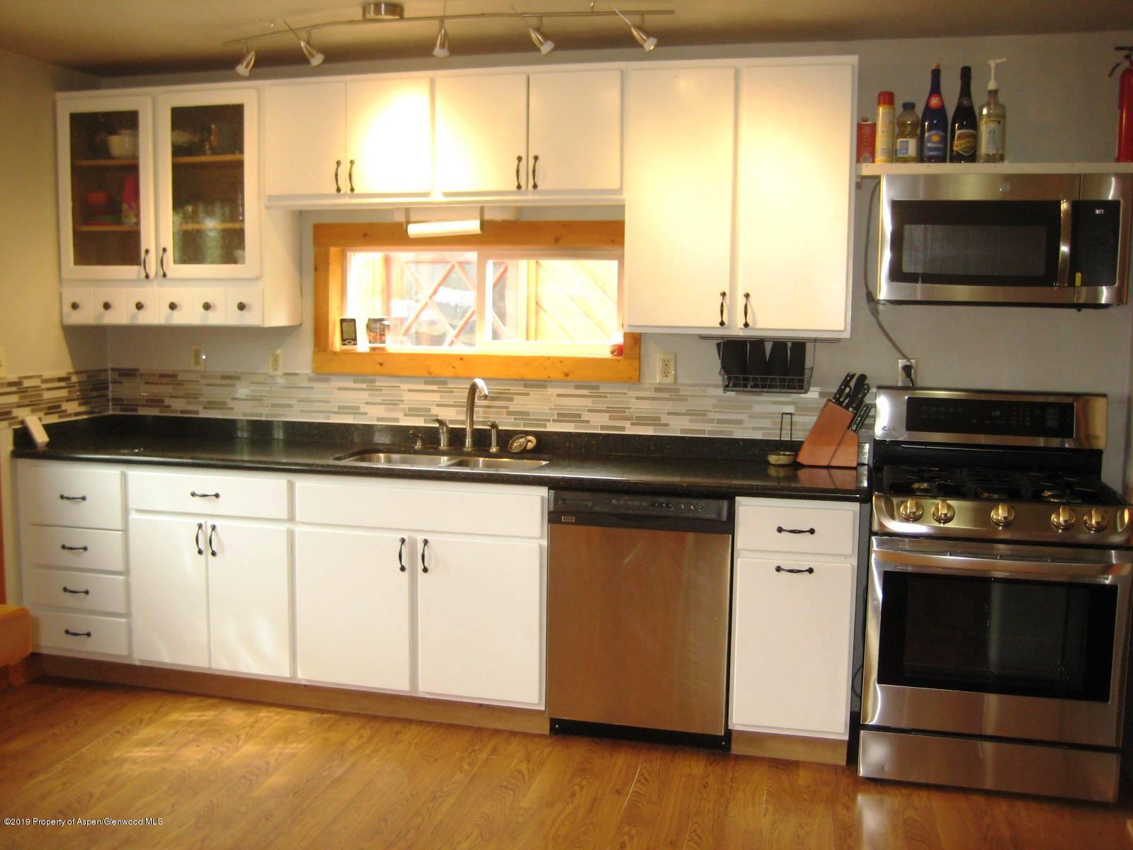 432 East 3rd Street Rifle, CO 81650 - Photo 5 of 20 a kitchen with granite countertop a stove a sink and a microwave