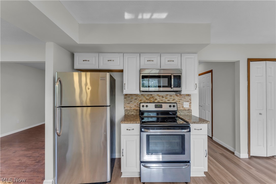 2540 Charney Road University Heights, OH 44118 - Photo 16 of 44 Kitchen featuring white cabinetry, granite-finish countertops, stainless steel appliances, a tiled backsplash, and wood-finish flooring
