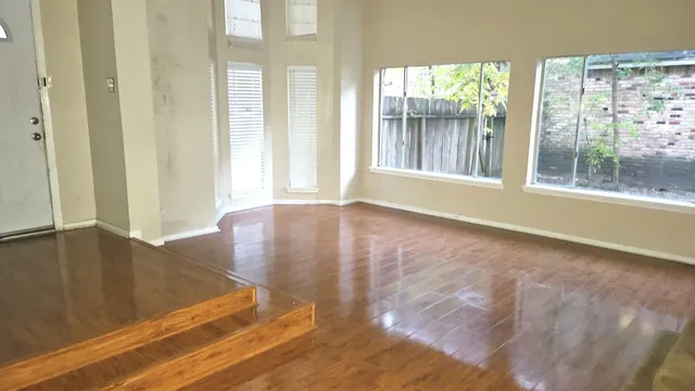 a view of an empty room with wooden floor and a window