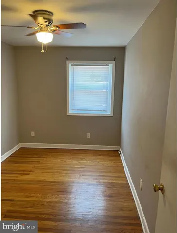 a view of an empty room with window and chandelier fan
