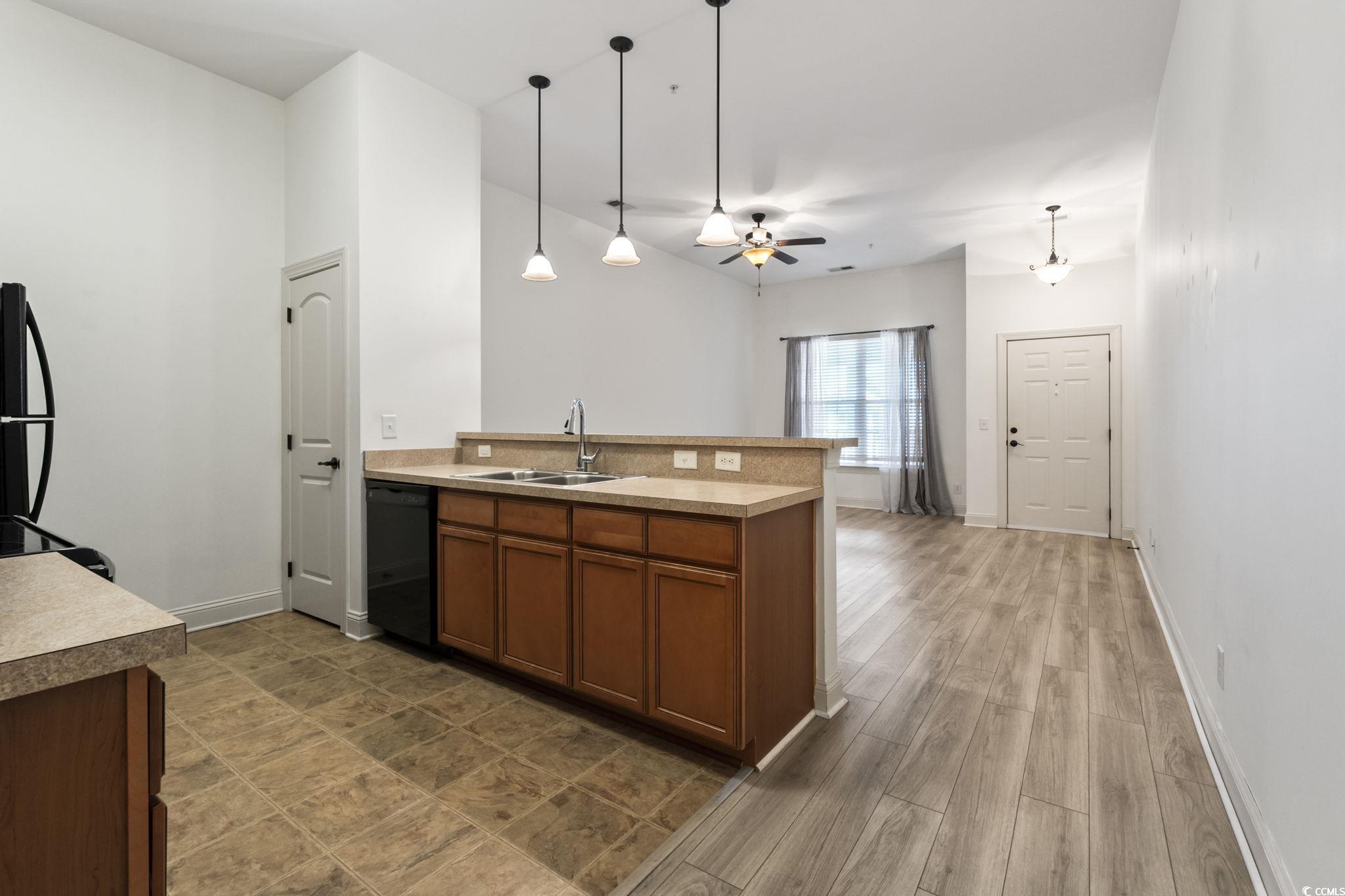 118 Ella Kinley Circle, Unit 404 Myrtle Beach, SC 29588 - Photo 12 of 22 Kitchen featuring a peninsula, brown cabinetry, hanging light fixtures, black appliances, and light countertops