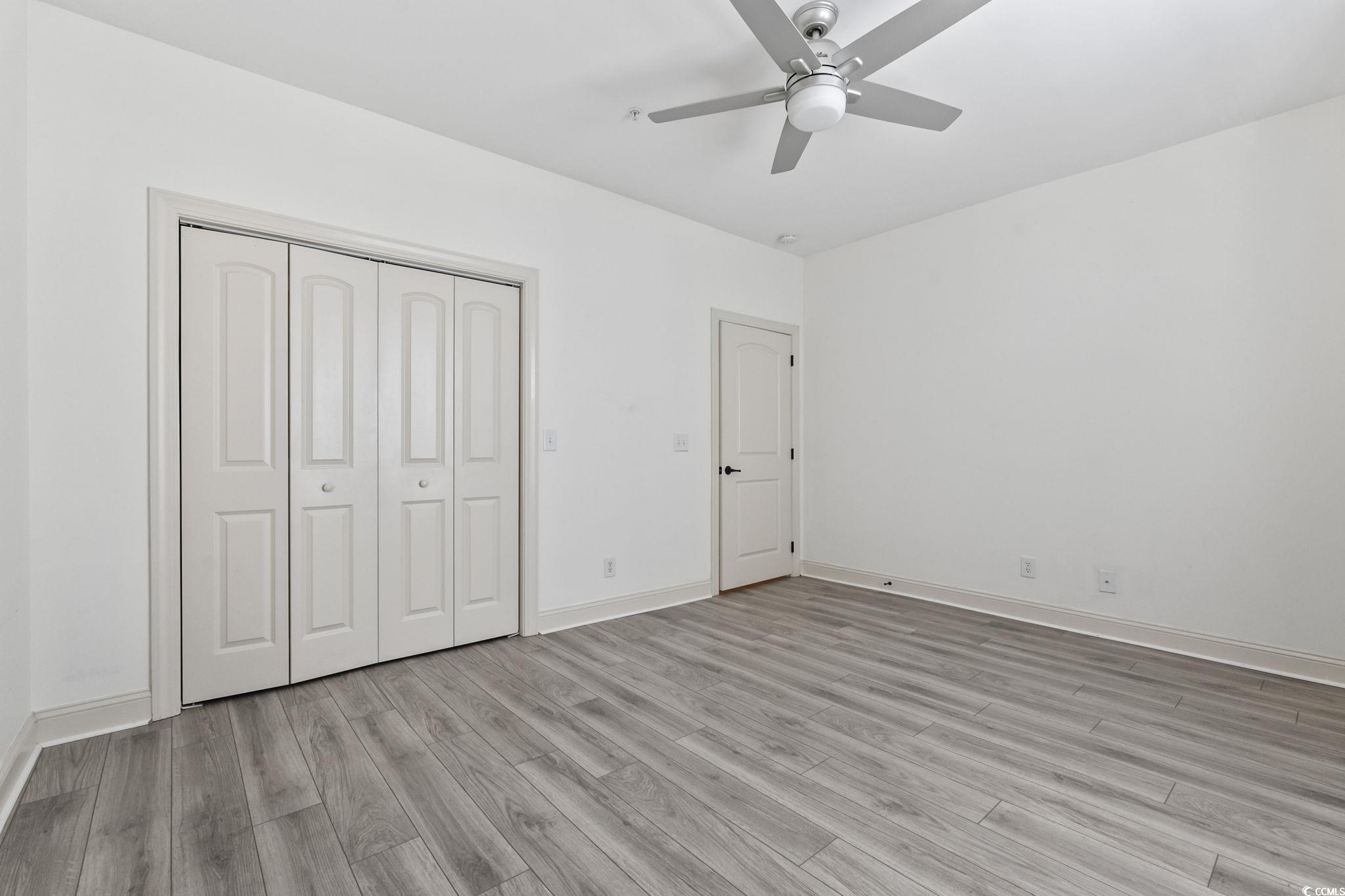 118 Ella Kinley Circle, Unit 404 Myrtle Beach, SC 29588 - Photo 18 of 22 Unfurnished bedroom featuring light wood-style flooring, ceiling fan, and a closet