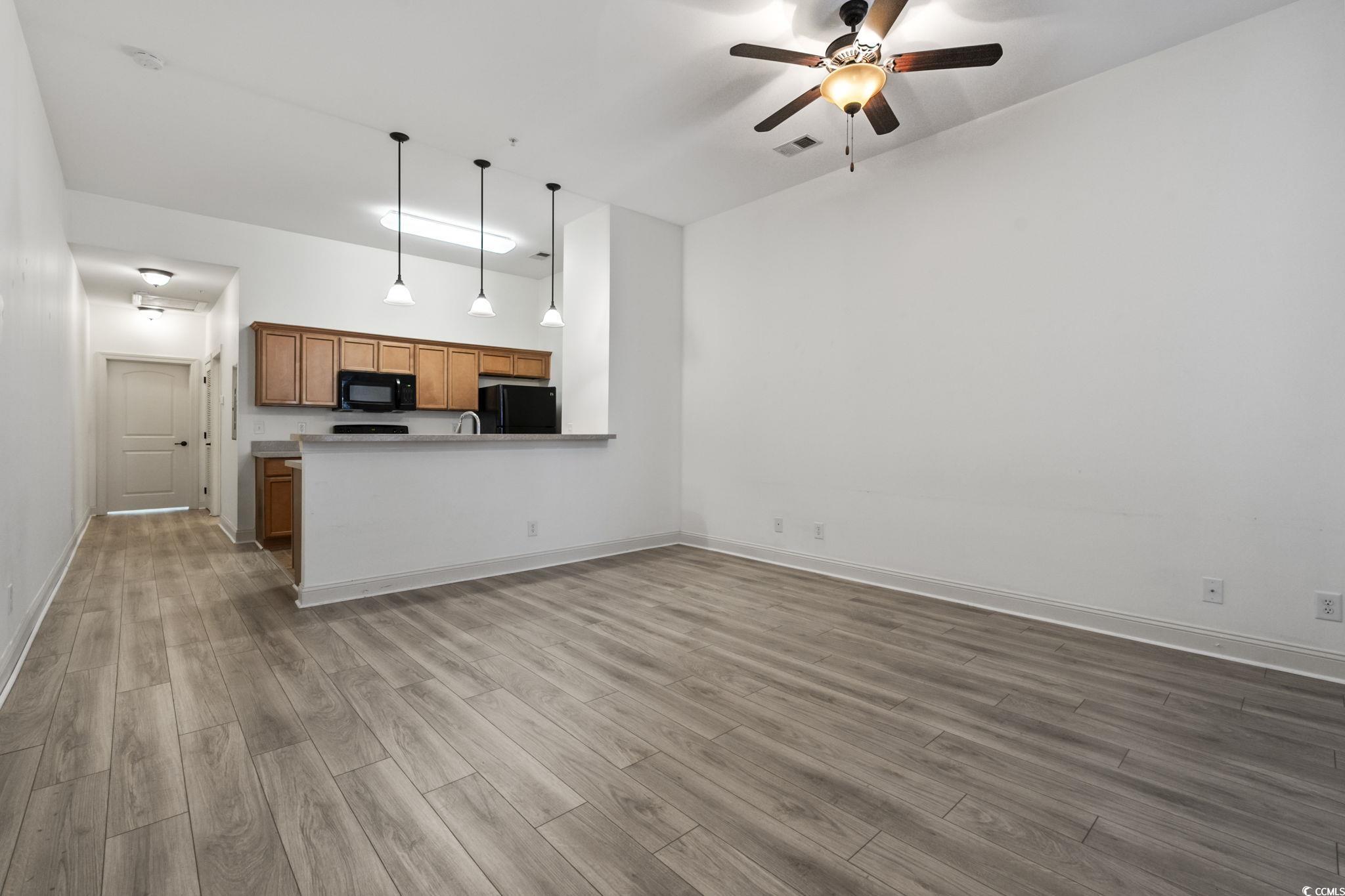 118 Ella Kinley Circle, Unit 404 Myrtle Beach, SC 29588 - Photo 5 of 22 Unfurnished living room featuring dark wood-type flooring and a ceiling fan