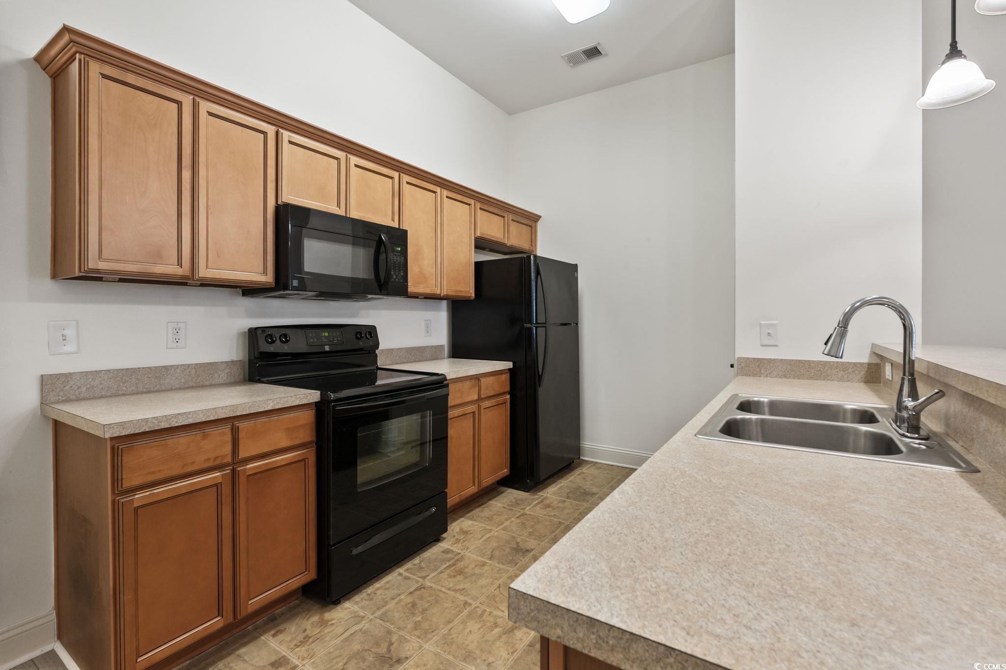 118 Ella Kinley Circle, Unit 404 Myrtle Beach, SC 29588 - Photo 9 of 22 Kitchen featuring black appliances, hanging light fixtures, brown cabinets, and light countertops