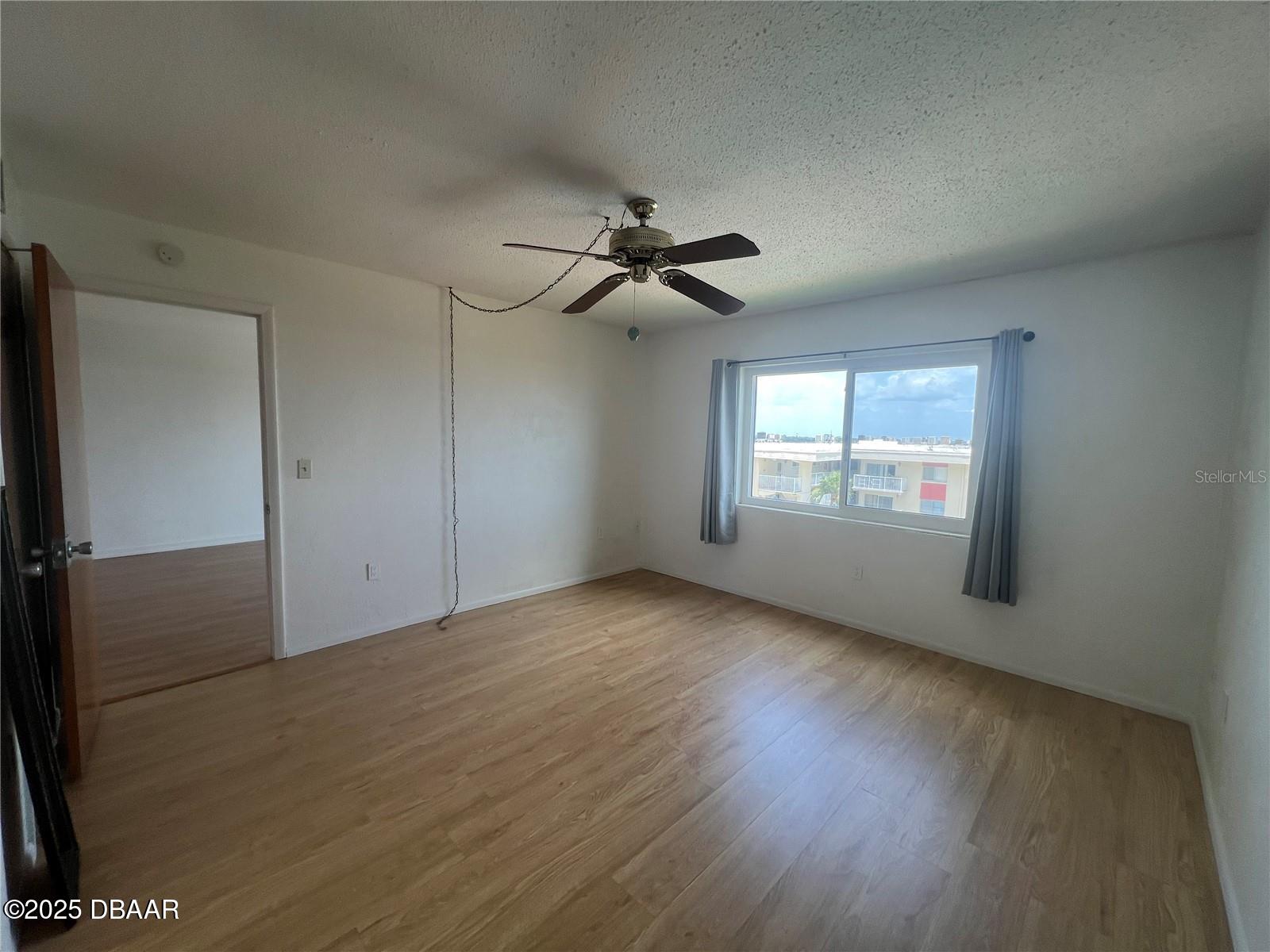 2711 North Halifax Avenue, Unit 593 Daytona Beach, FL 32118 - Photo 19 of 42 an empty room with wooden floor ceiling fan and windows