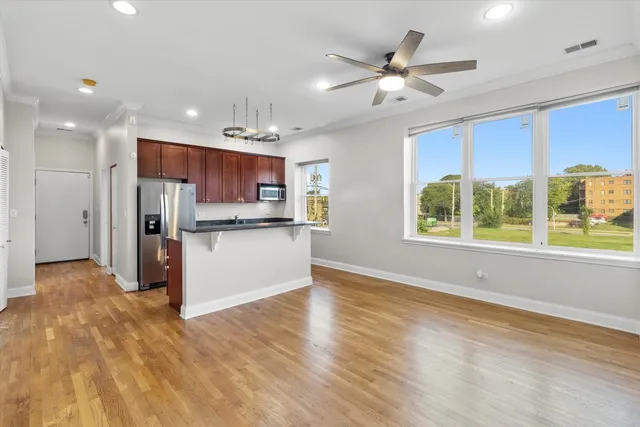 a large kitchen with stainless steel appliances granite countertop a refrigerator a sink dishwasher a stove and a microwave oven on the wooden floor