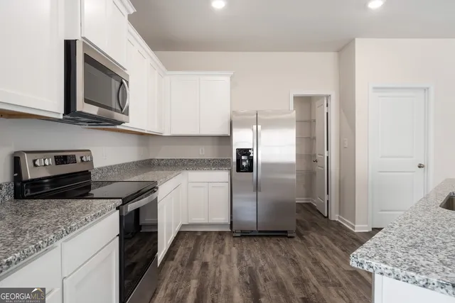 a kitchen with stainless steel appliances granite countertop a refrigerator a stove and a sink