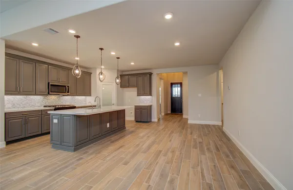 a large kitchen with a large counter top a sink stainless steel appliances and cabinets