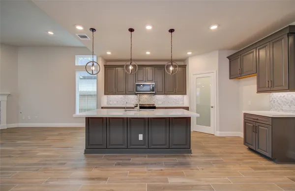 a large kitchen with stainless steel appliances granite countertop a large counter top a stove and a wooden floors