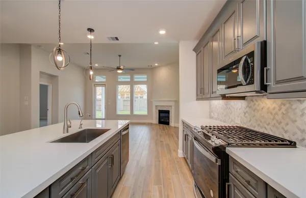 a large kitchen with stainless steel appliances a large counter top a sink a stove and a wooden floors