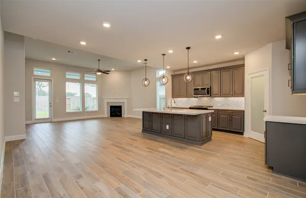 an empty room with wooden floor fireplace and windows