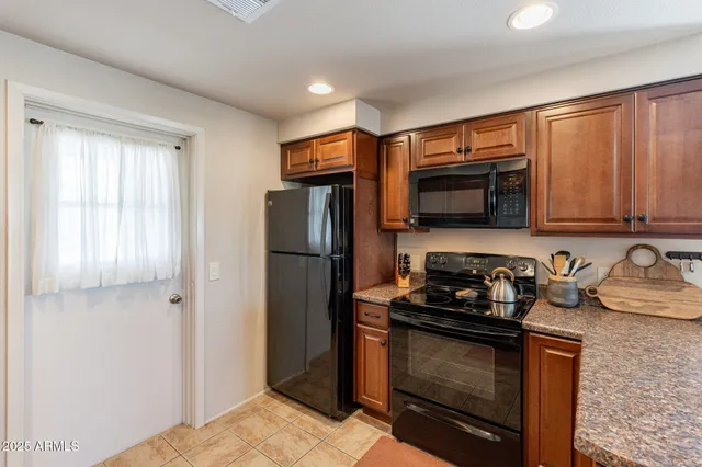 a kitchen with granite countertop stainless steel appliances a stove a refrigerator a sink a window and cabinets