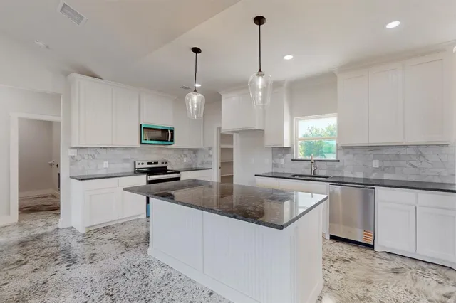 a kitchen with stainless steel appliances granite countertop a sink a stove top oven a counter space and cabinets