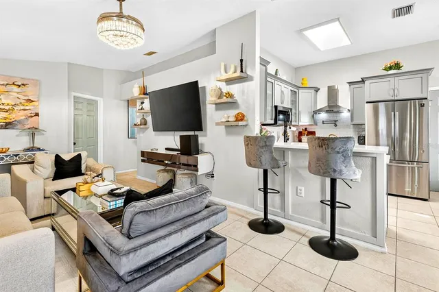 a dining room with stainless steel appliances furniture a chandelier and a kitchen view