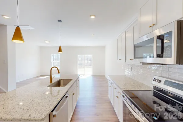 a kitchen with stainless steel appliances granite countertop a sink a stove and a wooden floors
