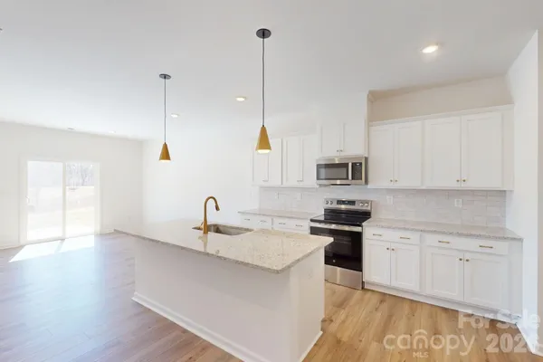 a kitchen with stainless steel appliances granite countertop a sink a stove and a refrigerator