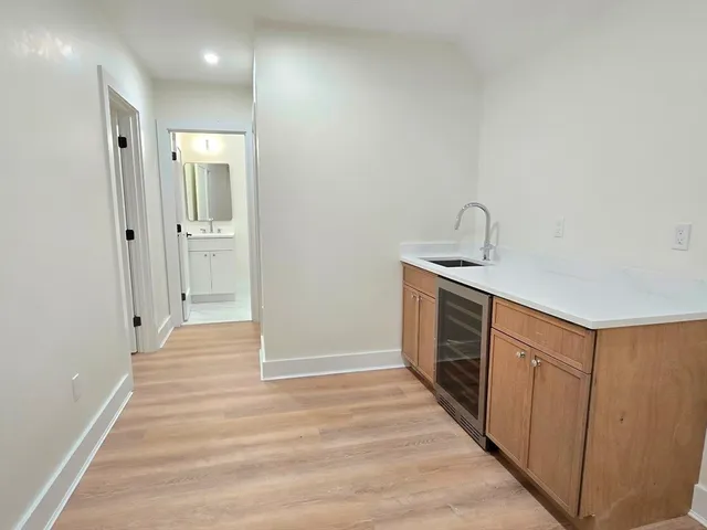a hallway view with stainless steel appliances granite countertop white cabinets and window