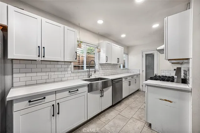 a kitchen with granite countertop white cabinets stainless steel appliances a sink and a window
