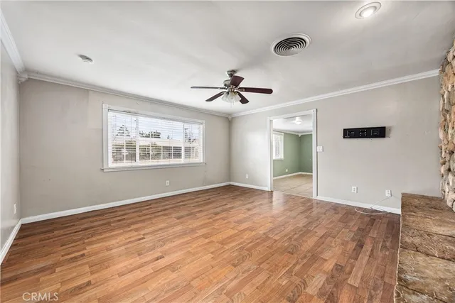 a view of an empty room with window and wooden floor